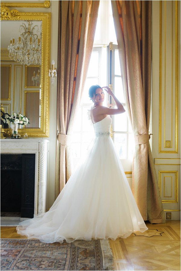 Beautiful bride poses in her drress in front of the Chateau windows