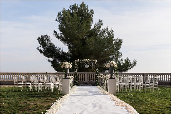 Outdoor wedding aisle complete with archway and rose petals