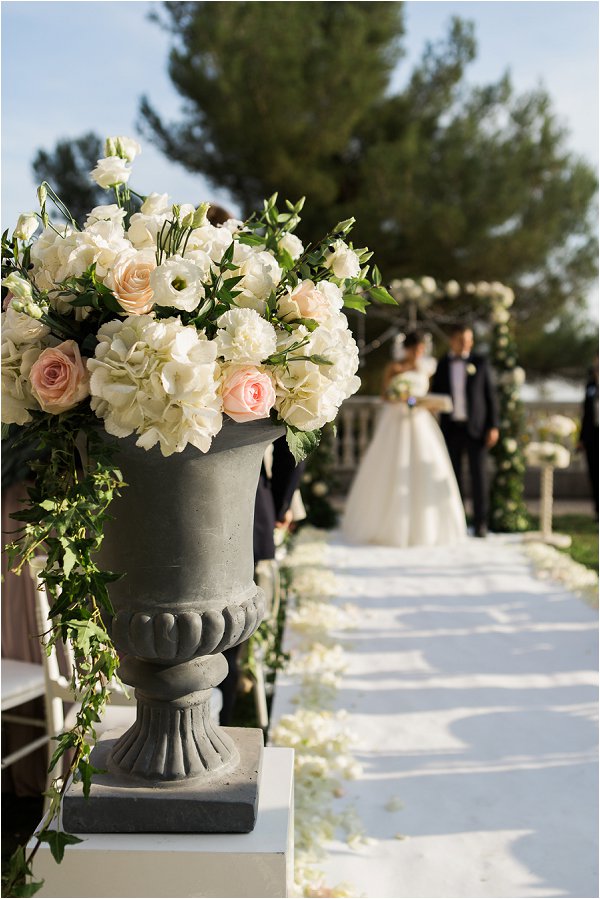 Pastel flowers in urn decorate the aisle