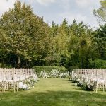 Outdoor wedding ceremony set up with white chairs on green grass