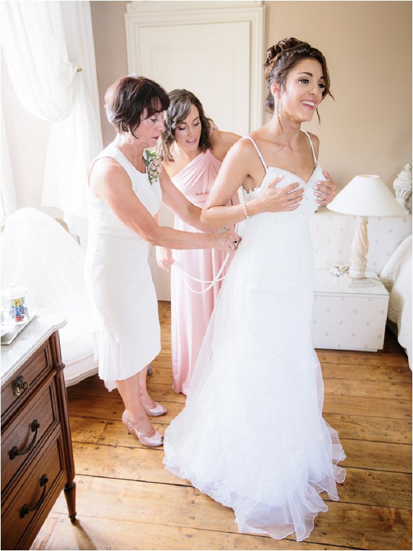 Mother of the bride and Bridesmaid fastening the brides dress