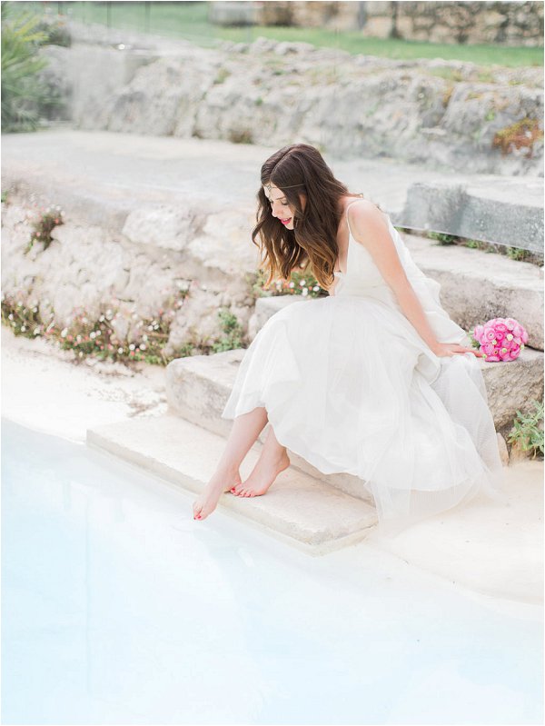 Bride dipping her toe into the swimming pool at Mas de la Rose in Provence