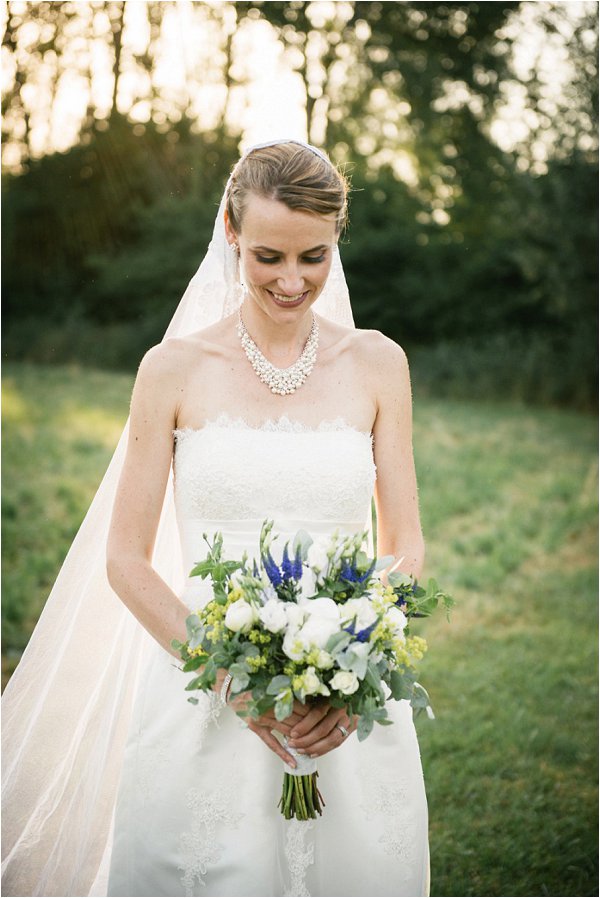 Blushing bride holding her white and blue bouquet