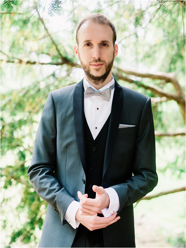 Groom in grey and black suit complete with silver bow tie