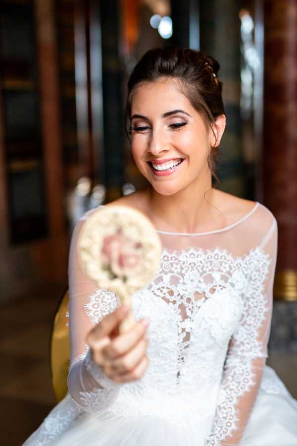 Bride looks in gilded hand mirror