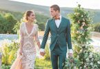 Newly-wed couple walk through gardens at pastel wedding