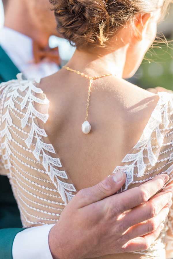 Back detail of brides dress and pearl necklace at nape of neck