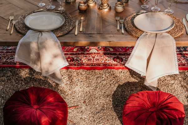 Red cushion seating and antique rug for outdoor asian themed wedding