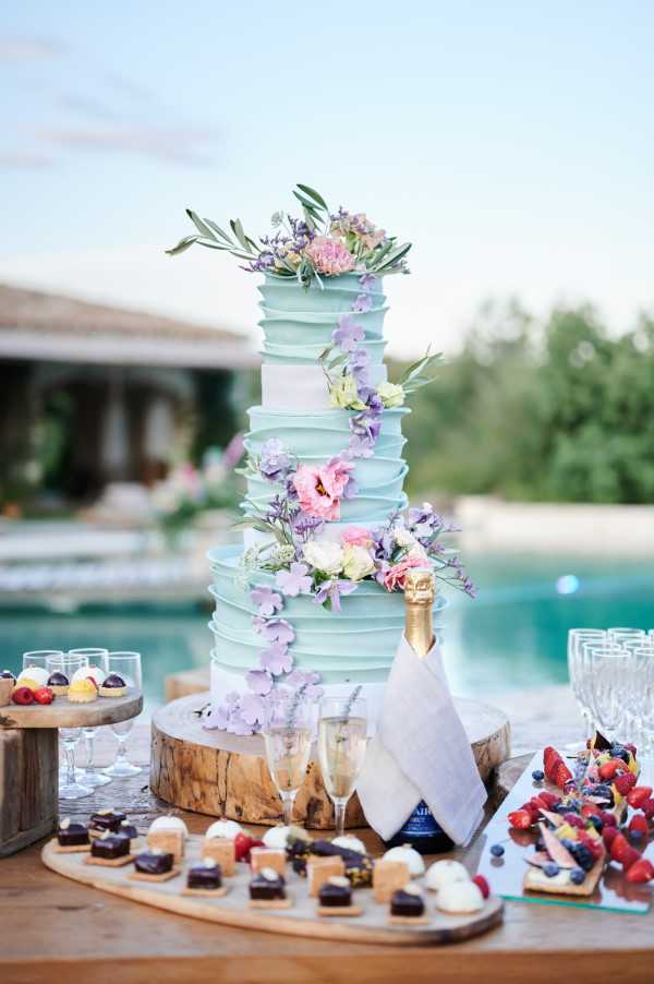 Beautiful 3 tier pastel blue wedding cake with rustic buttercream and fresh flowers