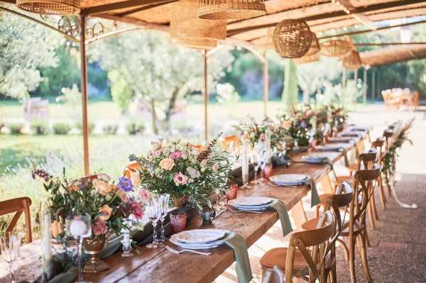 Rustic outdoor bridal table in converted stables with fresh flowers and raw wood table