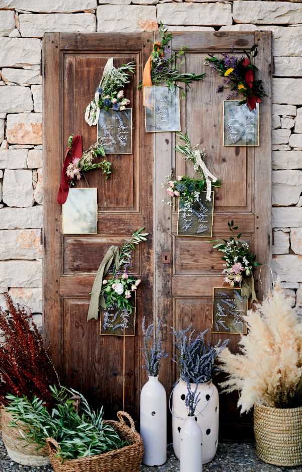 Porte-cochères doorway in raw wood with wedding seating plan and fresh flowers