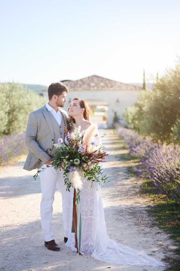 Bride and groom in bohemian style outfits with fresh bouquet in front of Domaine de Bres surrounded by Lavender