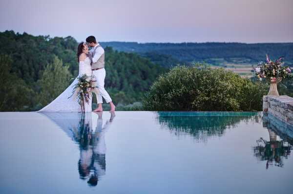 Bride and groom kiss at the edge of infinity pool