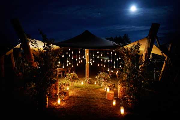 Hanging festoon lighting in the evening surrounded by candles by the Wedding Tents in the Lavender Meadows of Domaine de Bres