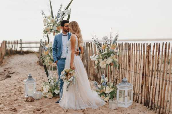 Beachside wedding ceremony with floral arbor and lanterns