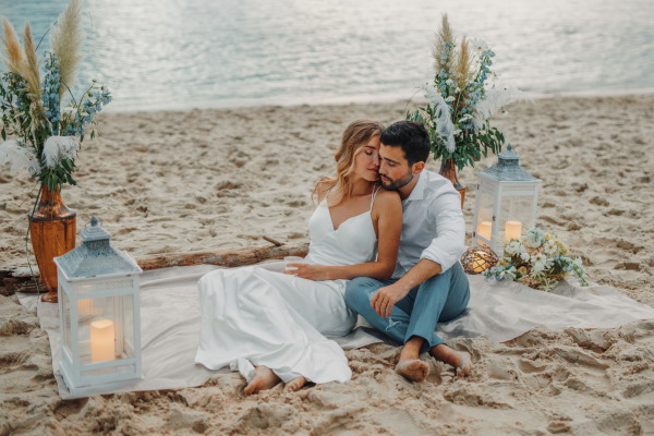 Couple relax on the sand lit by lantern at ocean wedding in Le Petit Nice in france