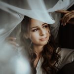 image of bride getting ready and the veil is draped over her and the photographer