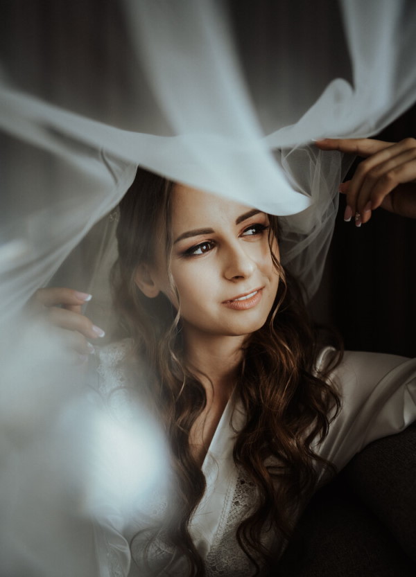 image of bride getting ready and the veil is draped over her and the photographer