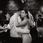 black and white image of bride dancing with groom she is smiling and his head is concealed behind hers