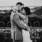 black and white image of bride with arms around grooms neck in a garden with a view