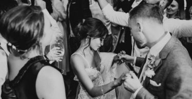 black and white image of bride dancing with groom she looks down and is holding his hand