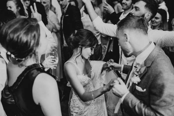 black and white image of bride dancing with groom she looks down and is holding his hand