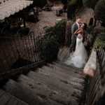 moody shot taken from the top of stairs looking down at bride and groom