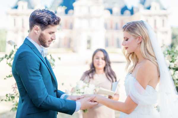 Bride and groom hold hands in front of celebrant in literary themed wedding