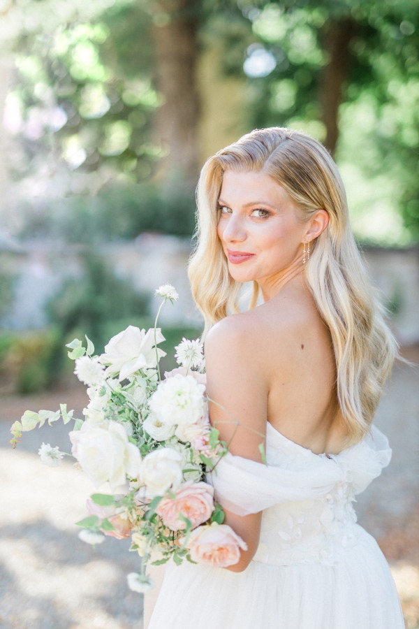 Bride looks back at camera over shoulder holding white and pink rose bouquet