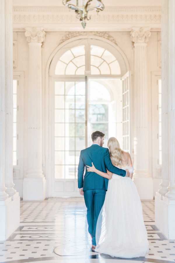 After literary wedding nuptials have finished the bride and groom walk the white halls of Chateau de Baronville arm in arm