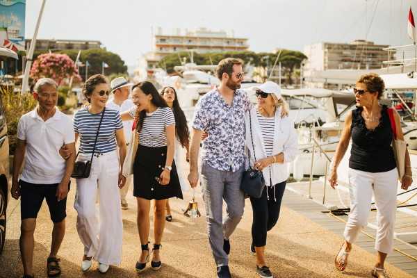 Friends and family walk together along yacht marina at Cote d'Azur France