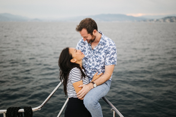 Couple pose at the bow of the yacht with a grey sea behind them