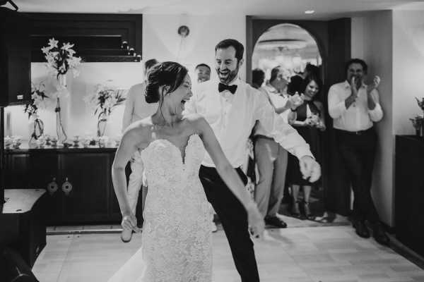 Black and white image of bride and groom dancing and smiling at wedding party