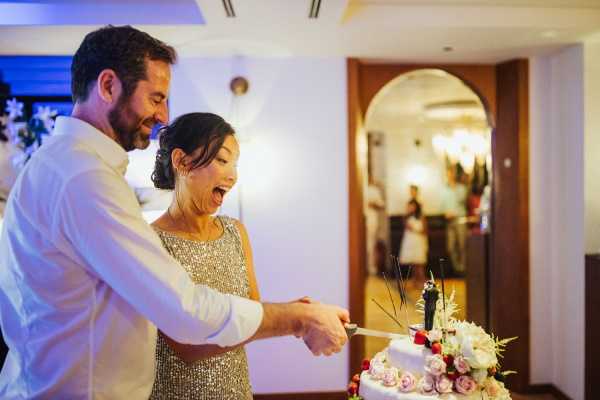 Bride and groom cut cake in going away outfits