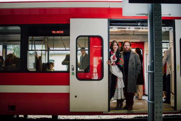 Bride and groom stand at the door of a red and white train in France which was caught to their sustainable wedding