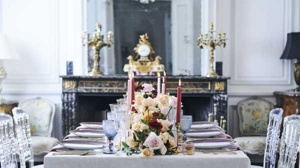 wedding table adorned with blue, burgundy and pink glasses, candles and floral arrangements