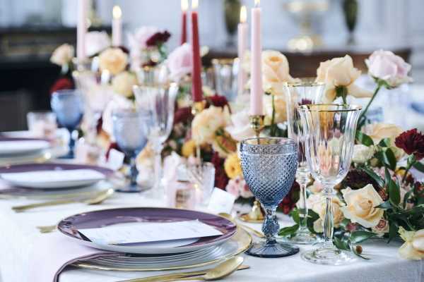 purple and gold rimmed plates and burgundy candles decorate the bridal table