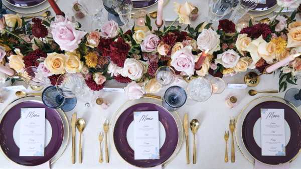 gold and purple plates, menu cards, burgundy floral arrangements at bridal table