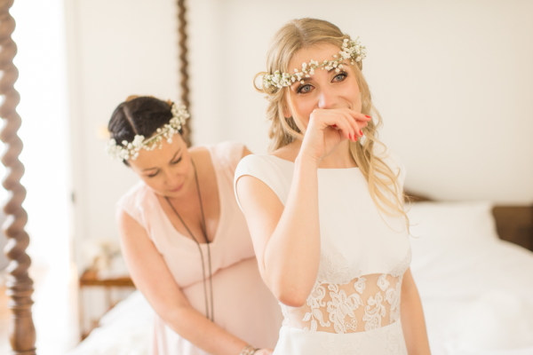 Bride is overcome with emotion as her bridesmaid does up her wedding dress 