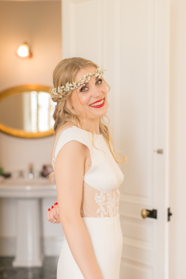 bride in red lipstick and flower crown smiles at camera