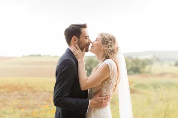 Bride and groom kiss after their elegant wedding at Chateau d'Azy in the fields