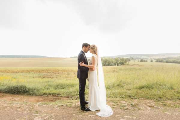 Bride and groom stand face to face in front of the field in the grounds of Chateau d'Azy