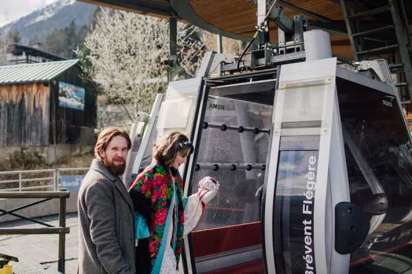 Bride and groom enter carriage of ski lift in french alps 