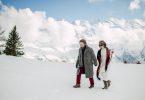 Bride and groom walk through the snow in boots in the French Alps in their suit and wedding dress