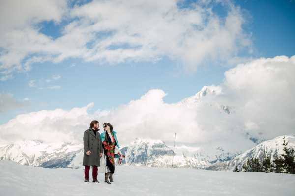 Newly married couple at the top of snowy mountain in the French Alps with snowcapped mountains behind them