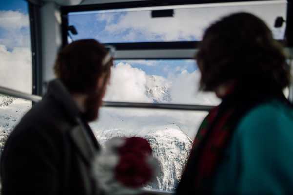 Silhouette of bride and groom looking out of ski lift at French Alps below