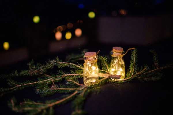 Recycled fir tree branch and small jars filled with fairy lights adorn wedding tables