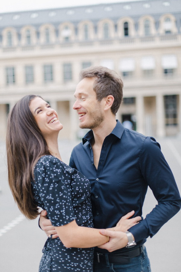 Couple laugh in navy blue attire outside the Palais du Louvre