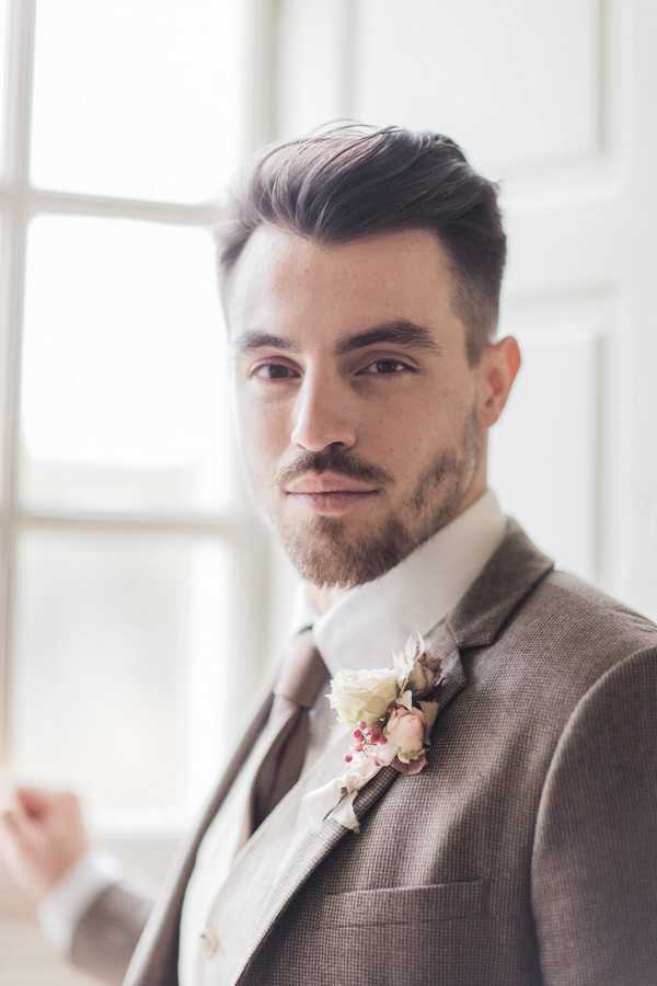 groom in brown tweed suit and brown tie looks into camera