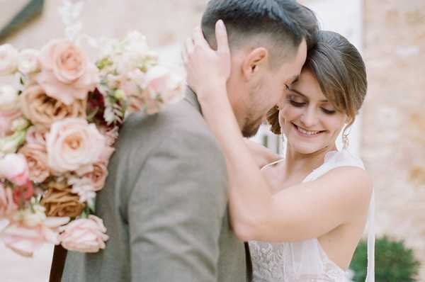 bride and groom embrace and hold pink bouquet